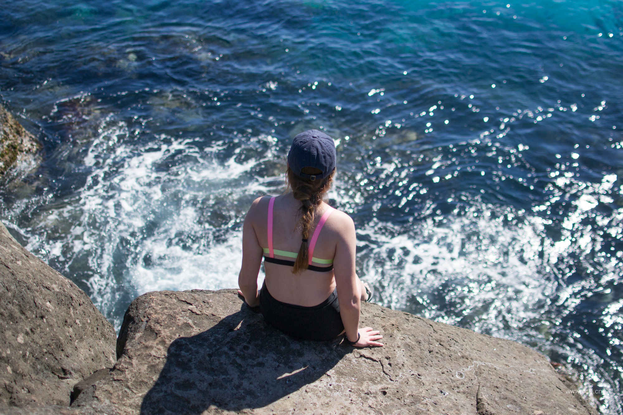 坐在岸边岩石上的女生人物背影