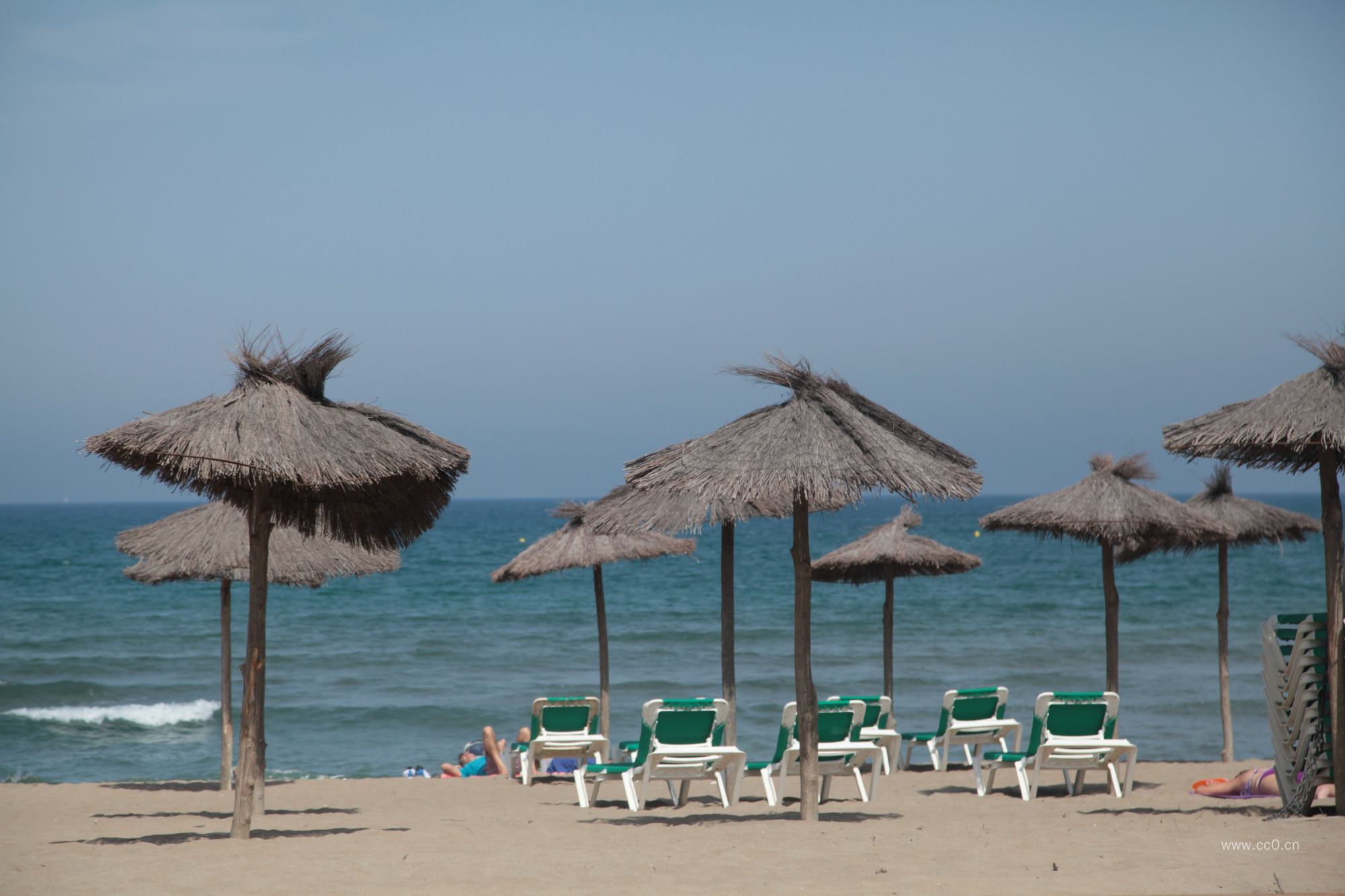 夏日海滩的休闲椅与茅草凉亭