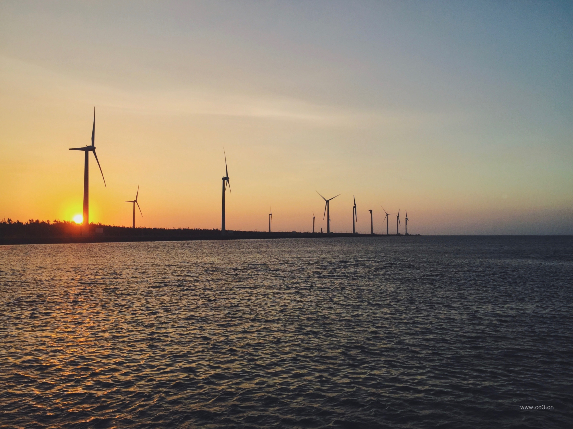 海边的风力发电风车与日出图片