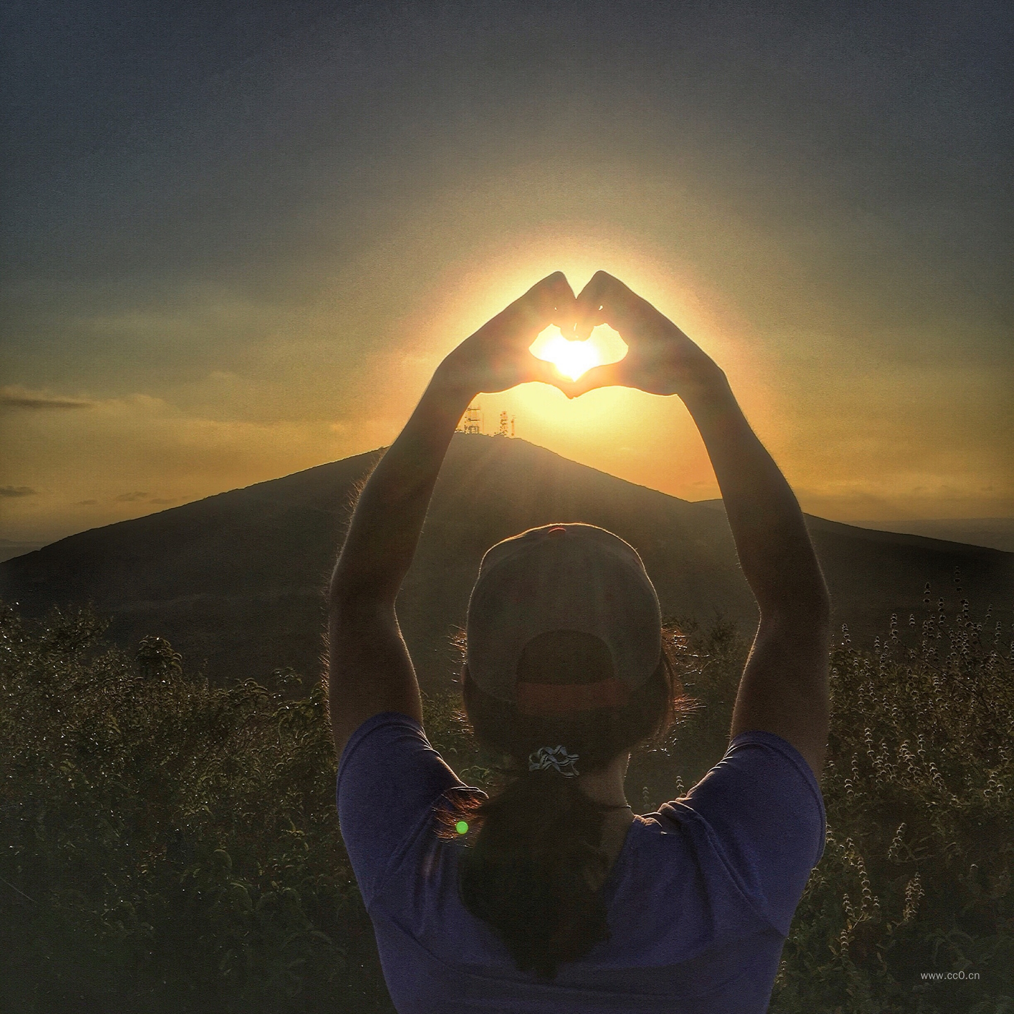 比着桃心手势看日出的女生背影