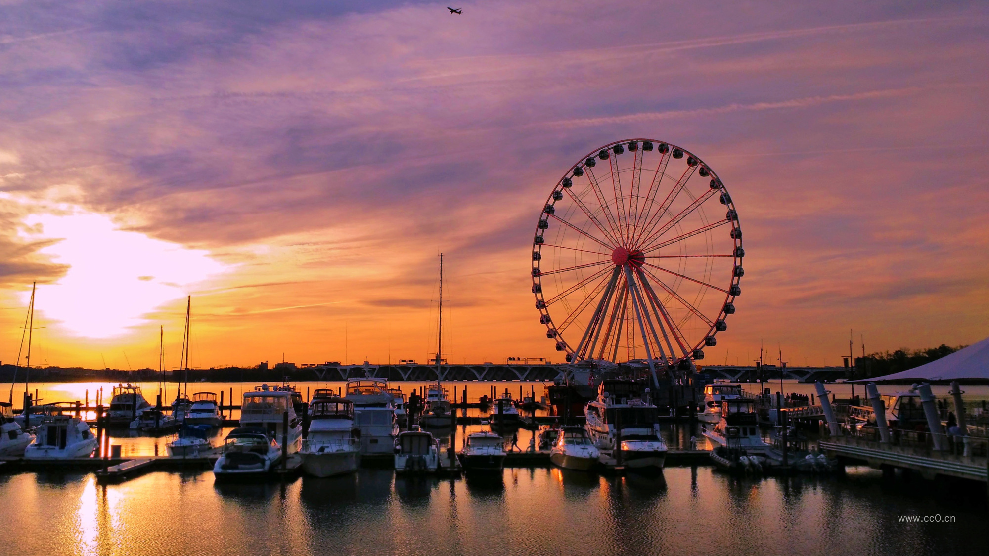 晚霞天空下港口的船只与摩天轮