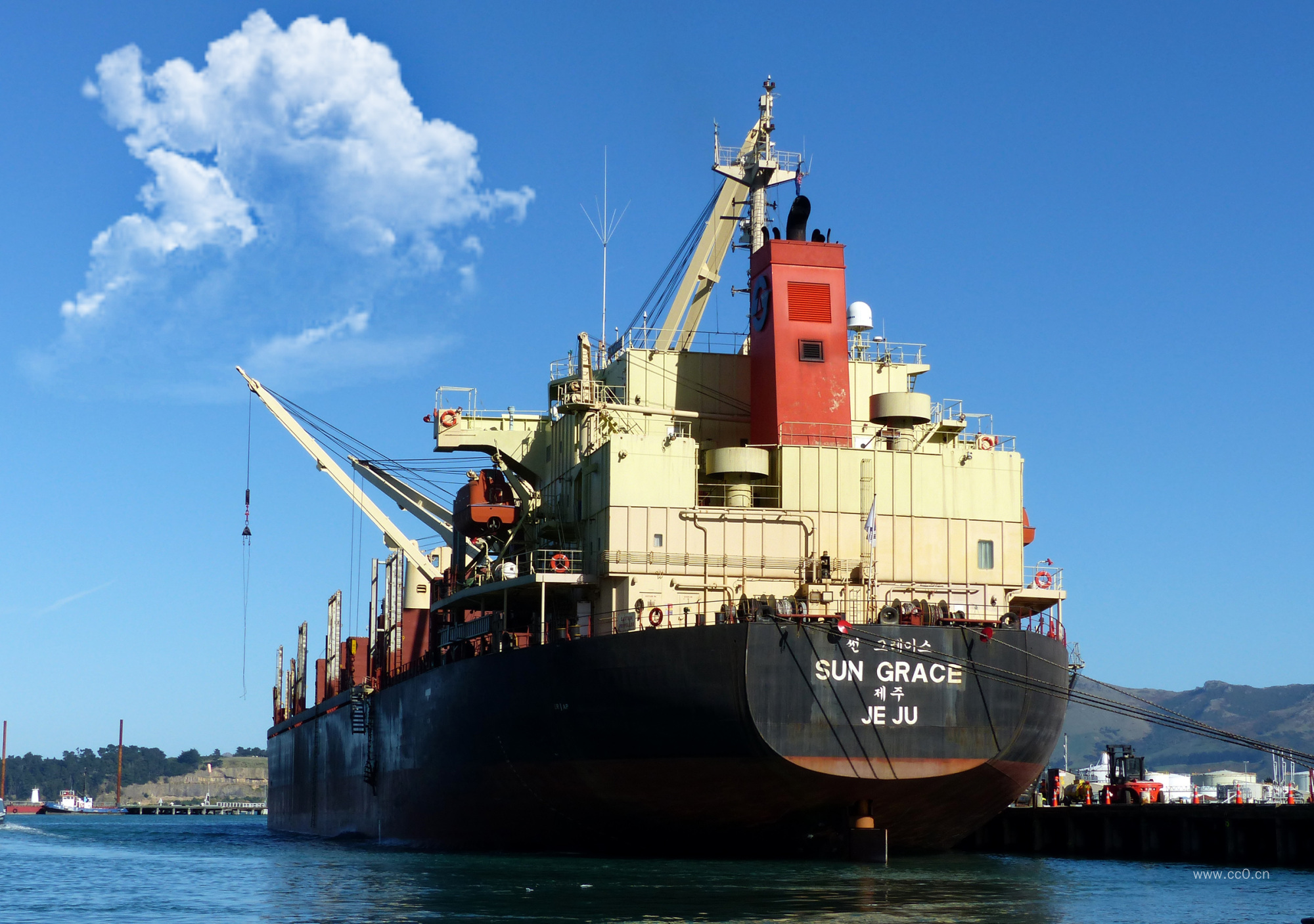 蓝天白云下停泊在海港的一艘货轮图片