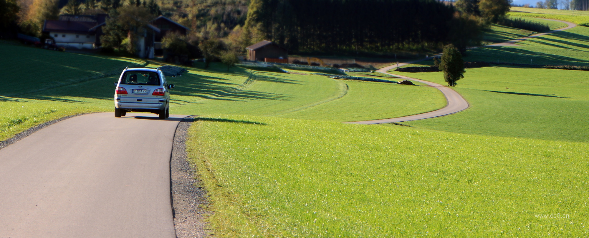 草坪与蜿蜒乡村公路上行驶的汽车